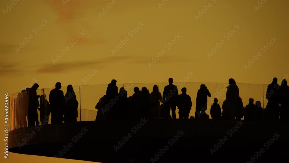 Silhouettes of unknown tourists on observation deck in the evening, slow motion tele shot