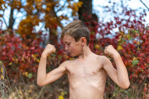 Young Boy Looking at His Flexed Arm Muscle photo