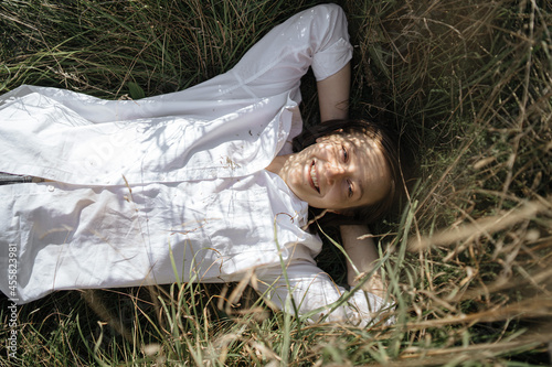 young laughing woman lies in the grass in nature photo