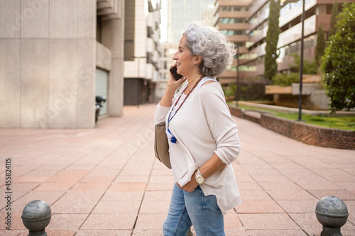 Side view of mature woman talking with her cell phone in an urban area photo