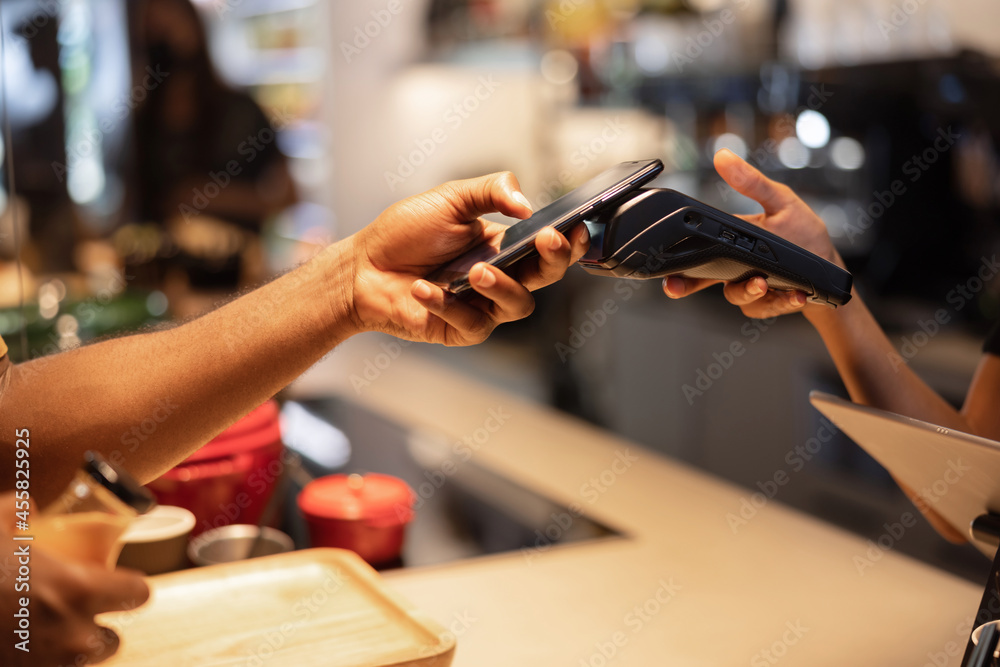 Crop client making contactless payment on POS terminal in cafe Crop client making contactless payment on POS terminal in cafe