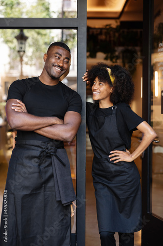 Delighted black waiter and waitress standing near cafe photo
