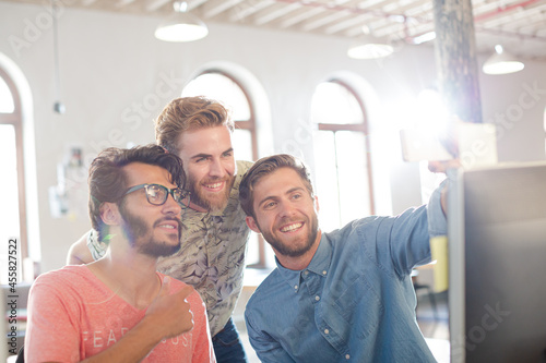 Creative business people taking selfie with instant camera in office