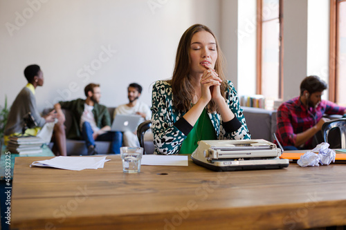 Creative businesswoman reviewing paperwork at typewriter in office