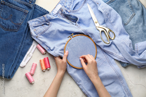 Fényképezés Woman sewing jeans on light background
