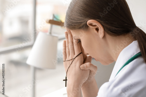 Praying female doctor in cl...