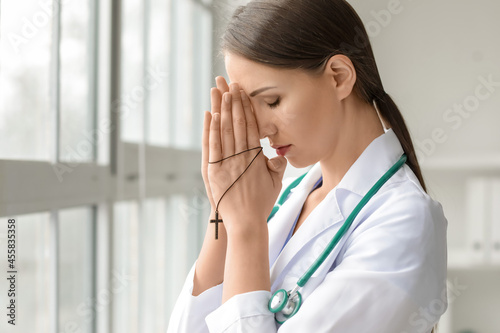 Praying female doctor in cl...