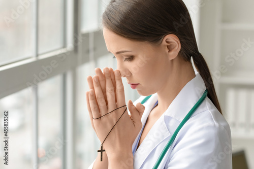 Praying female doctor in cl...