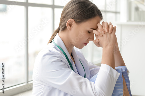 Praying female doctor in cl...
