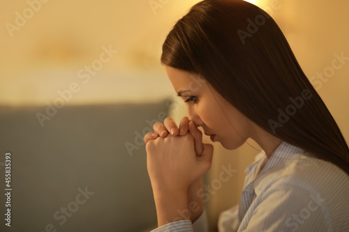 Praying young woman at home...