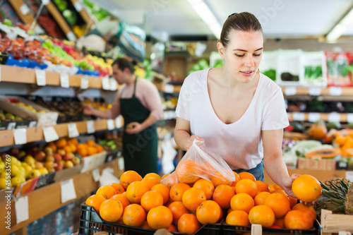 Glad woman customer choosing fresh oranges on the supermarket © JackF