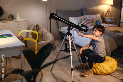 Little boy looking at stars through telescope in evening