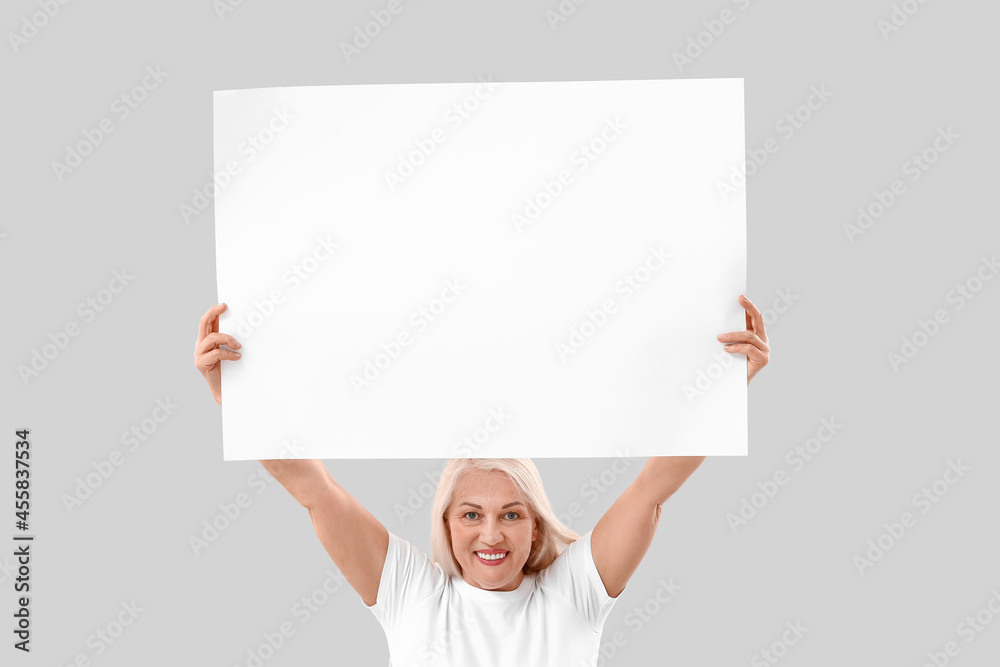 Mature woman with blank poster on light background Mature woman with blank poster on light background