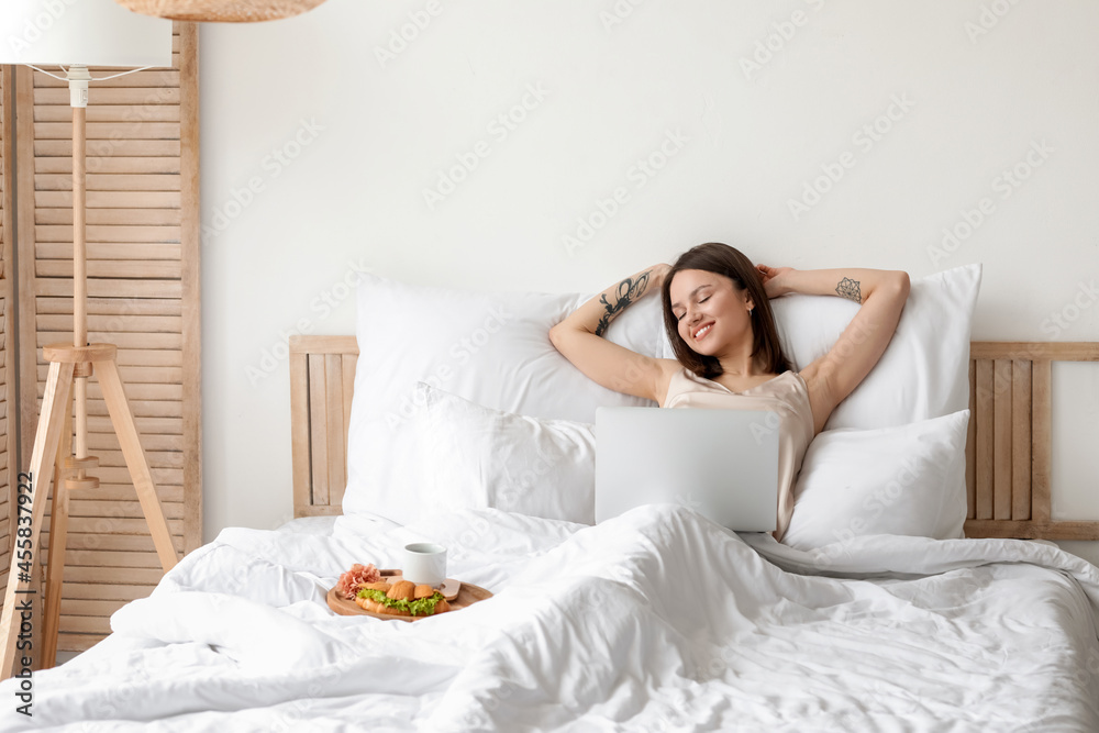 Young woman with laptop in bedroom