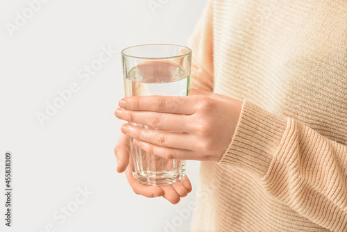 Woman with glass of water on light background