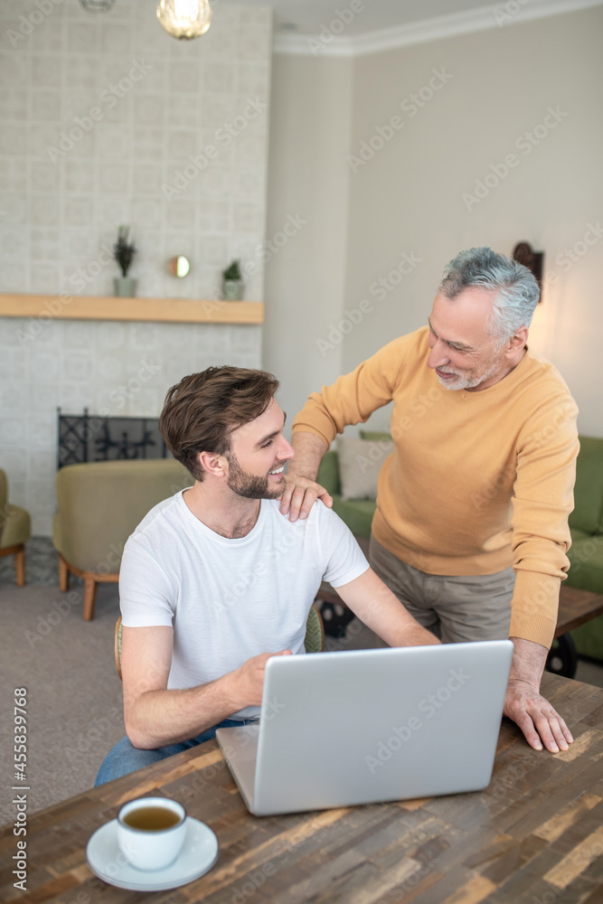 Fototapeta premium Two men watching something on a laptop and looking involved