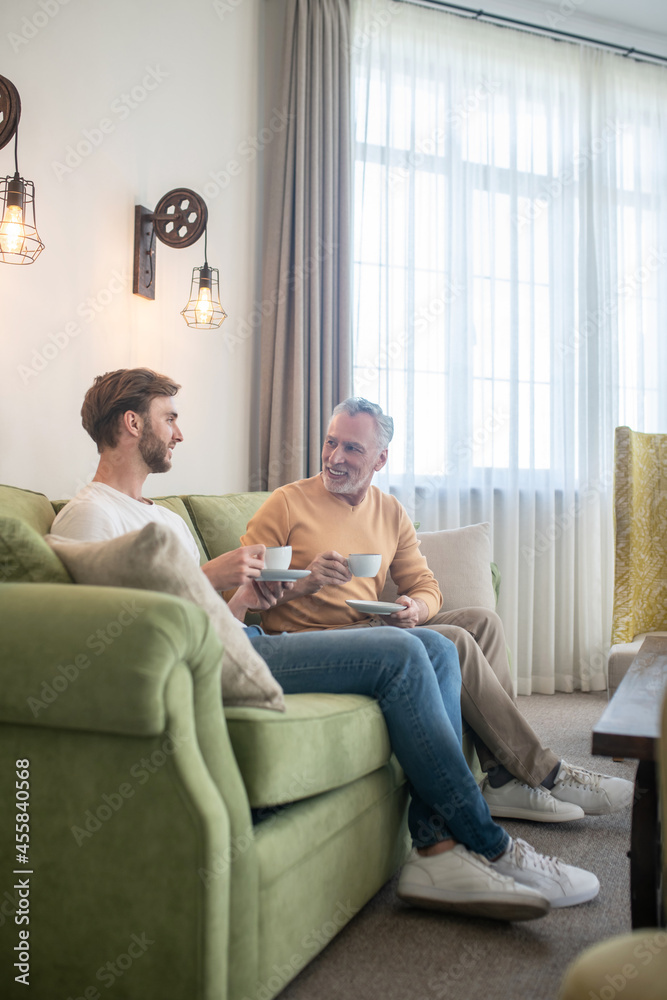 Two men sitting on the sofa and having tea Two men sitting on the sofa and having tea