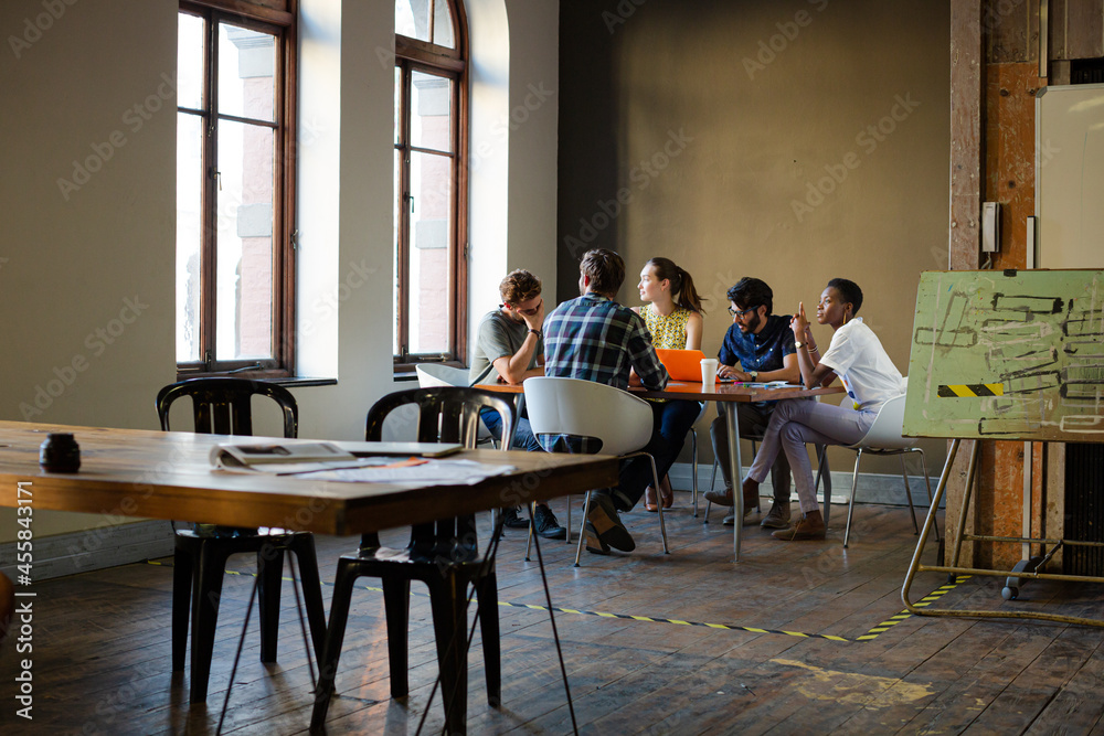Creative business people working at tables in sunny office Creative business people working at tables in sunny office