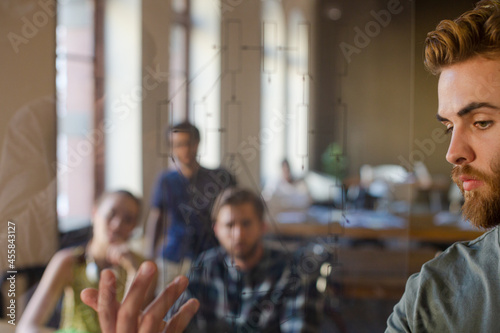 Casual businessman explaining diagram on glass in meeting