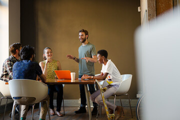 Creative business people working at tables in sunny office