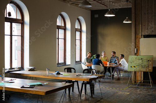 Creative business people working at tables in sunny office