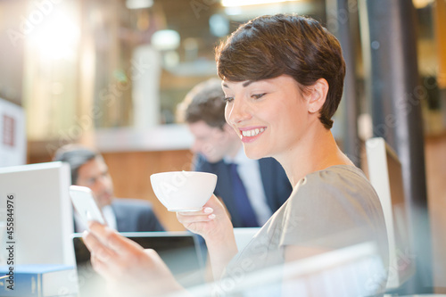 Smiling businesswoman drinking coffee in office