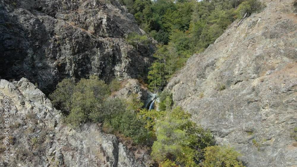 Aerial view towards a waterfall in the mountains of sunny Cyprus - tilt, drone shot Aerial view towards a waterfall in the mountains of sunny Cyprus - tilt, drone shot