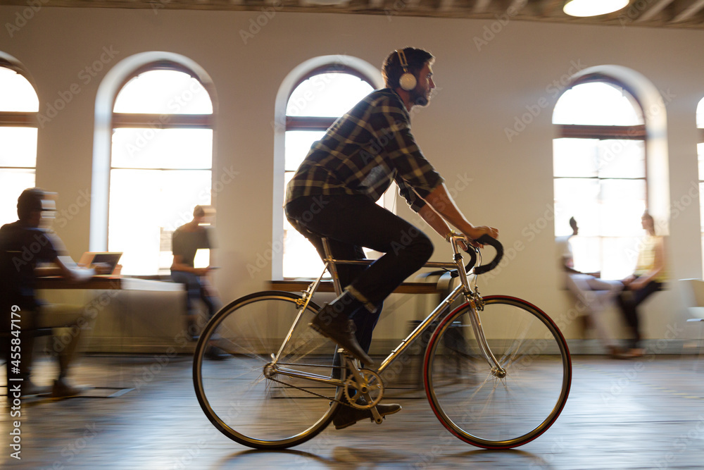 Fototapeta premium Casual businessman riding bicycle in open office