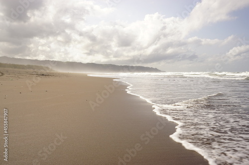 Soft waves of the sea on a sandy beach on a cloudy sky background. landscape beach