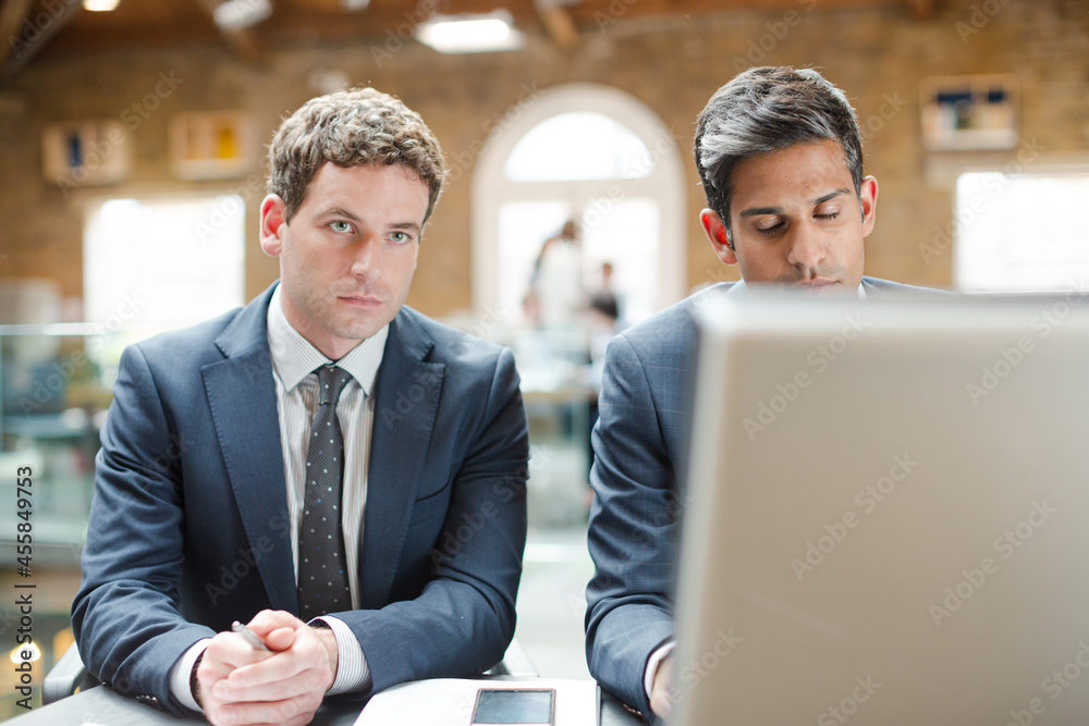 Businessmen working at computer in conference room Businessmen working at computer in conference room