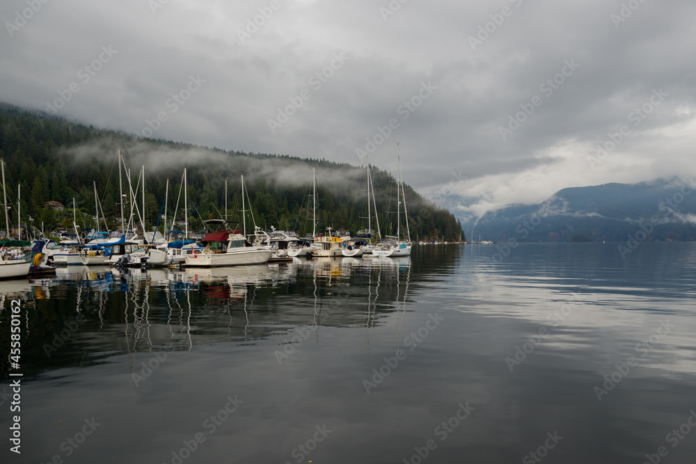Fototapeta premium The anchor yacht in harbor After rain cloudy sky, misty forest mountains and calm water.
