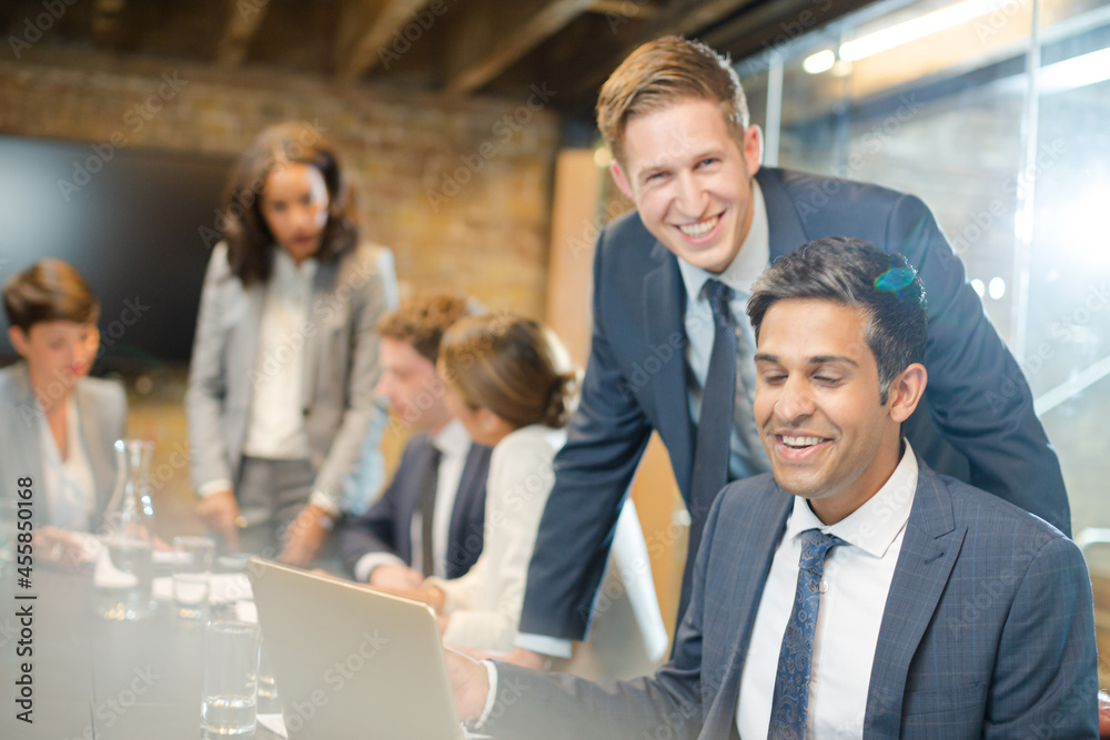 Obraz premium Businessmen smiling at laptop in conference room meeting