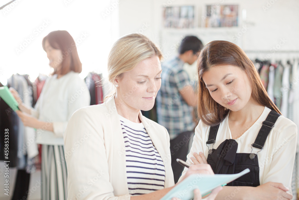 Fashion designer watching assistant taking notes Fashion designer watching assistant taking notes