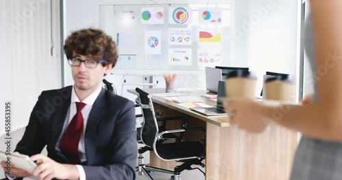 Wallpaper Mural Businessman sitting and working in concentrate and focus at desk while businesswoman buddy colleague brings cups of coffee walking to him with care and concern. Good team and friendship idea. Torontodigital.ca