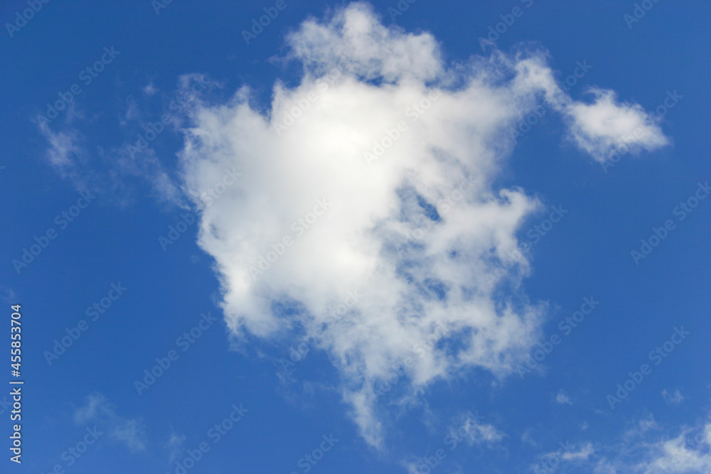 A white fluffy cloud drifts through a dreamy blue sky