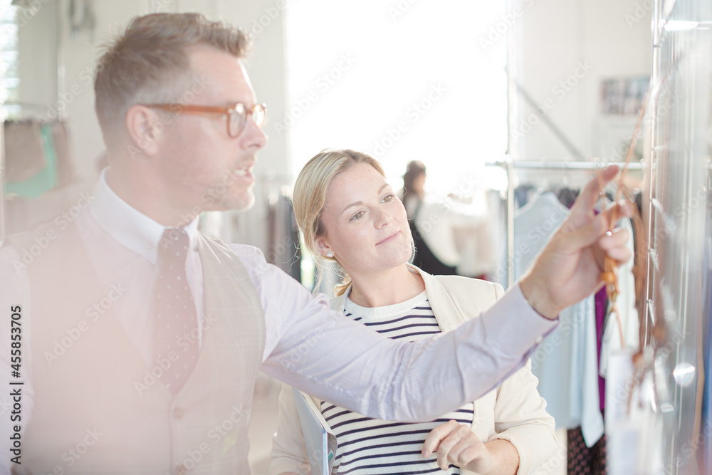 Fototapeta premium Fashion designers examining clothing on racks