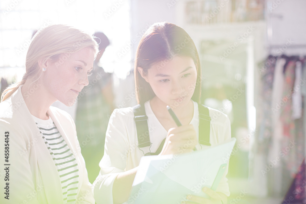 Fashion designer watching assistant taking notes Fashion designer watching assistant taking notes