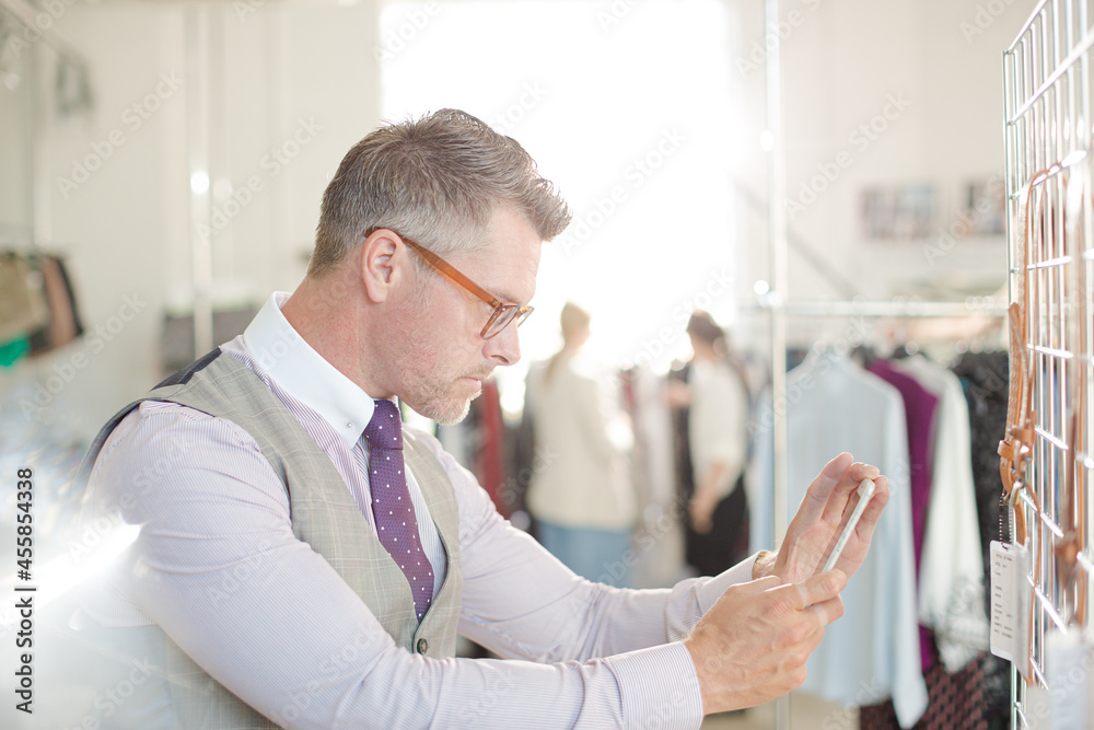 Fototapeta premium Fashion designer examining clothing on racks