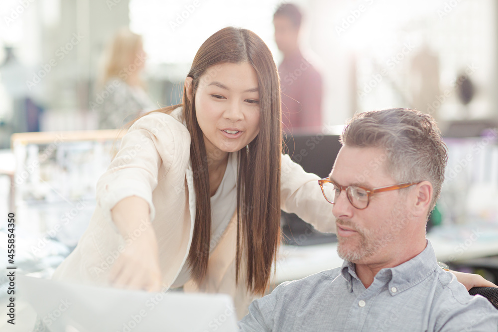 Fashion designers reviewing paperwork in office Fashion designers reviewing paperwork in office