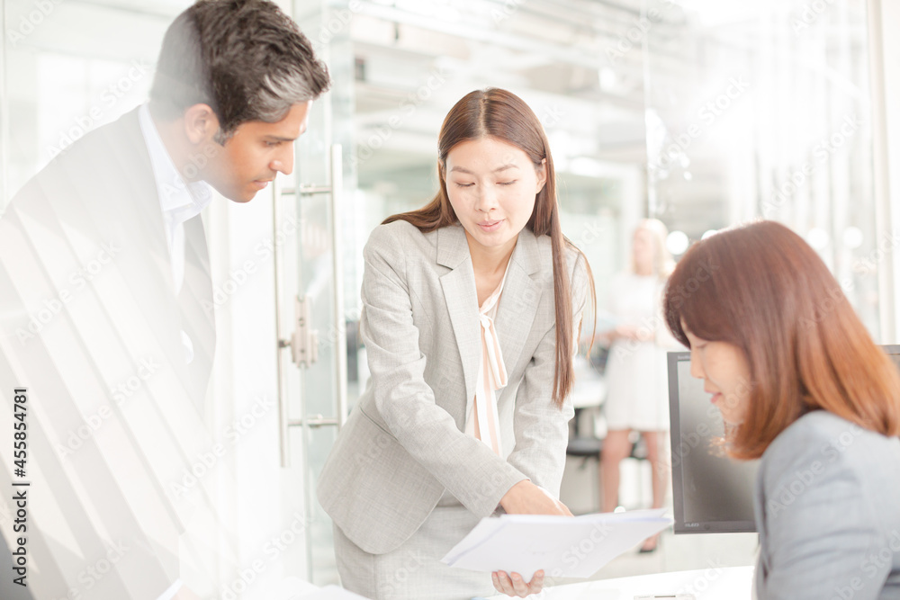 Business people reviewing paperwork at desk in office Business people reviewing paperwork at desk in office