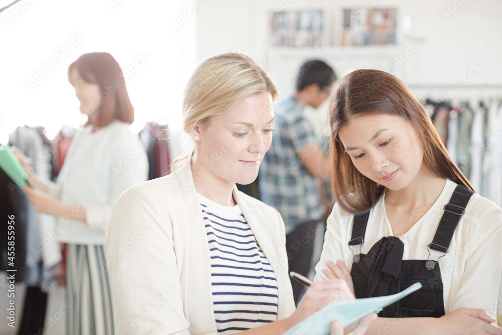 Fashion designer watching assistant taking notes Fashion designer watching assistant taking notes