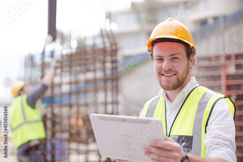 Portrait confident construction worker digital tablet at construction site
