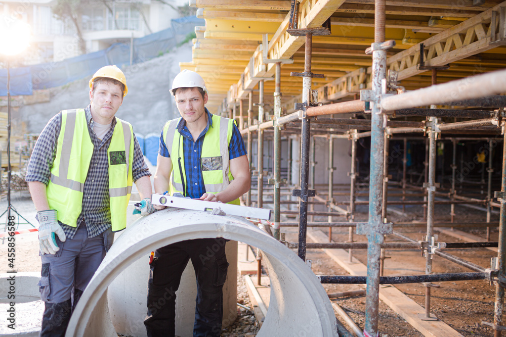 Portrait confident engineers with clipboard at construction site Portrait confident engineers with clipboard at construction site