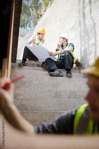 Construction workers engineer reviewing blueprints at construction site
