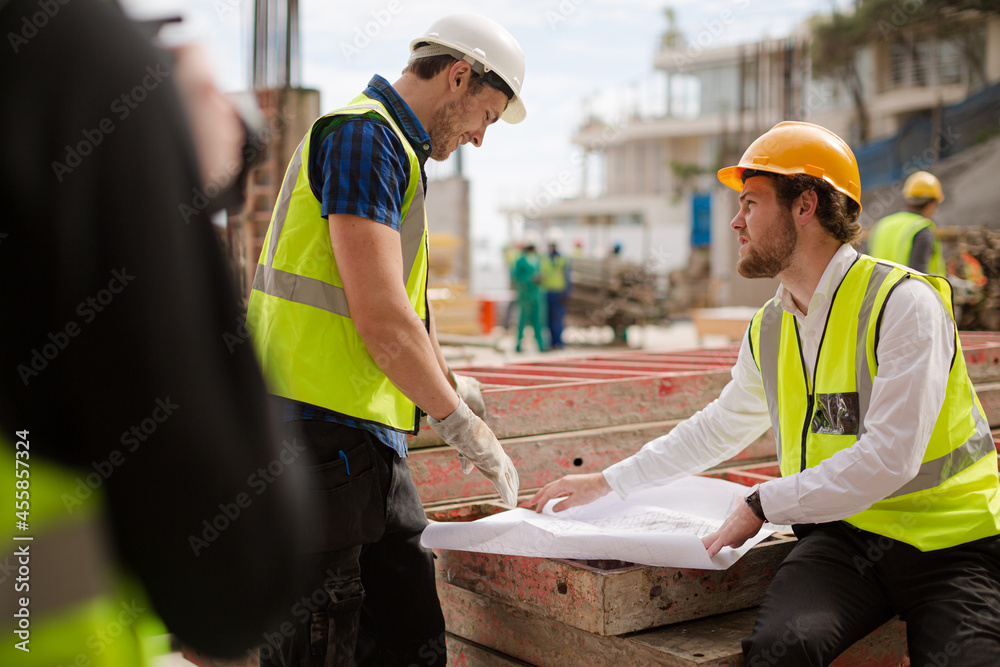 Construction worker engineer reviewing blueprints at highrise construction site Construction worker engineer reviewing blueprints at highrise construction site