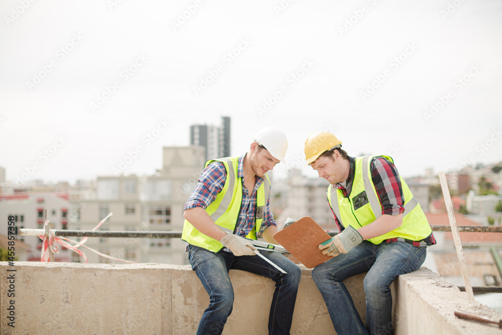 Construction worker engineer clipboard talking at highrise construction site
