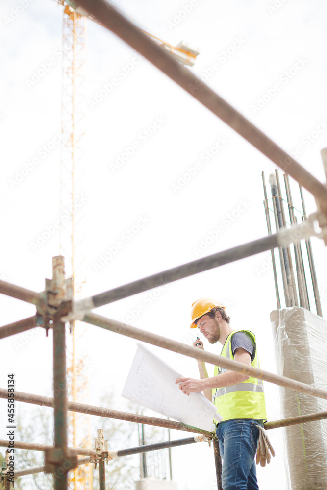Engineer reviewing blueprints at high rise construction site
