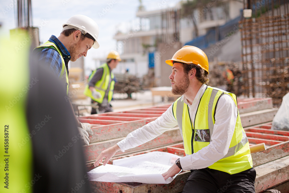 Construction worker engineer reviewing blueprints at highrise construction site Construction worker engineer reviewing blueprints at highrise construction site