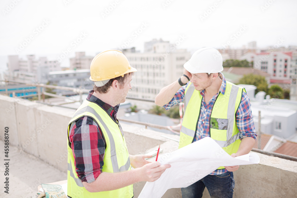 Construction worker engineer reviewing blueprints at highrise construction site Construction worker engineer reviewing blueprints at highrise construction site
