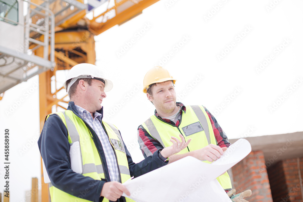 Construction worker engineer reviewing blueprints at highrise construction site Construction worker engineer reviewing blueprints at highrise construction site